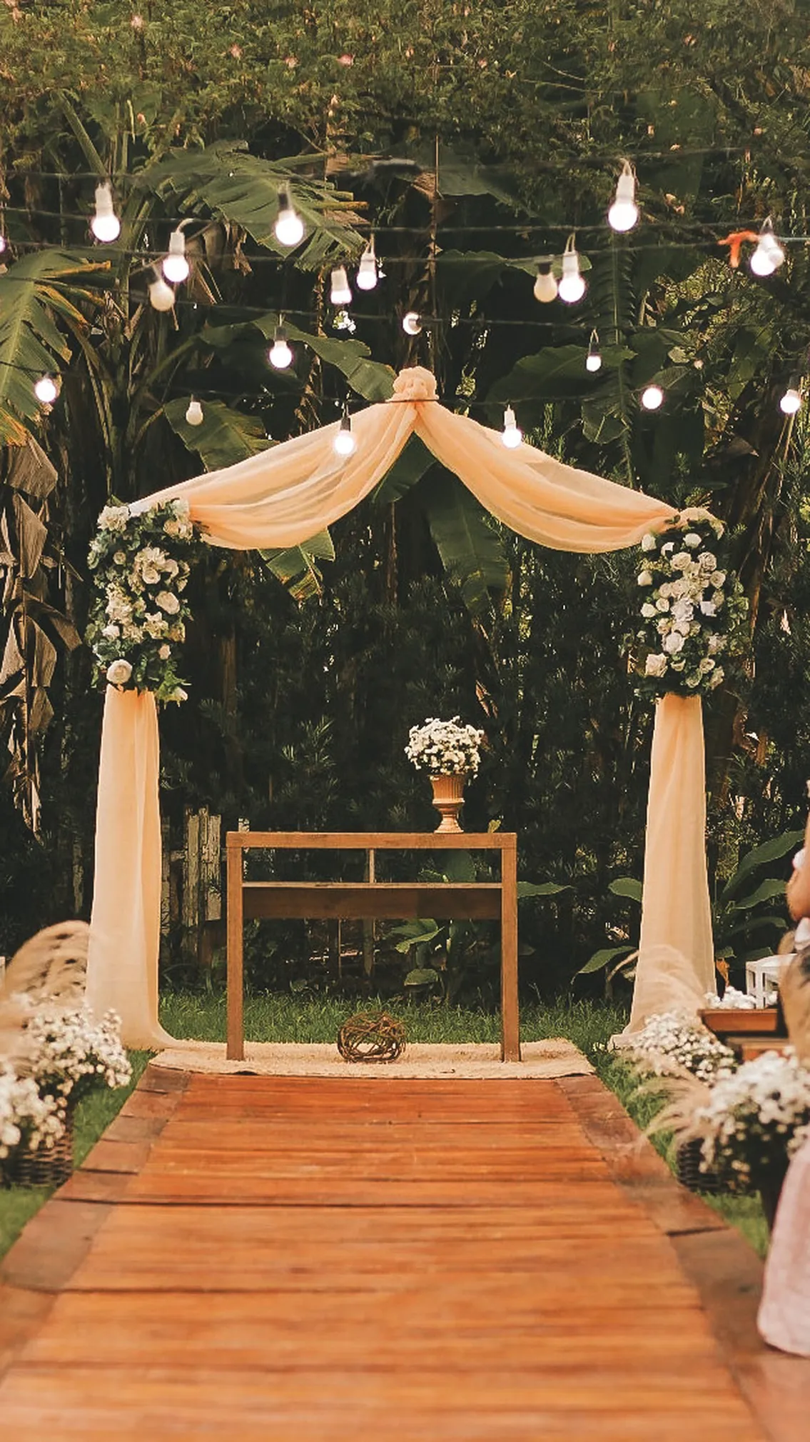 Cerimônia ao ar livre no Espaço Lia Coelho, com arco floral e tecido drapeado