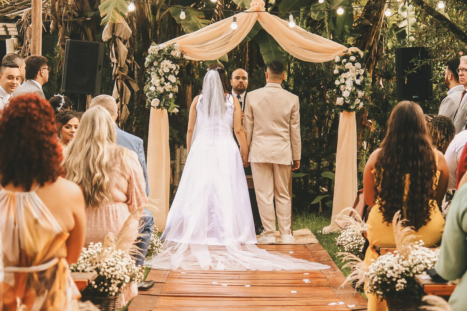 Cerimônia de casamento no Espaço Lia Coelho, com os noivos ao altar sob o arco floral